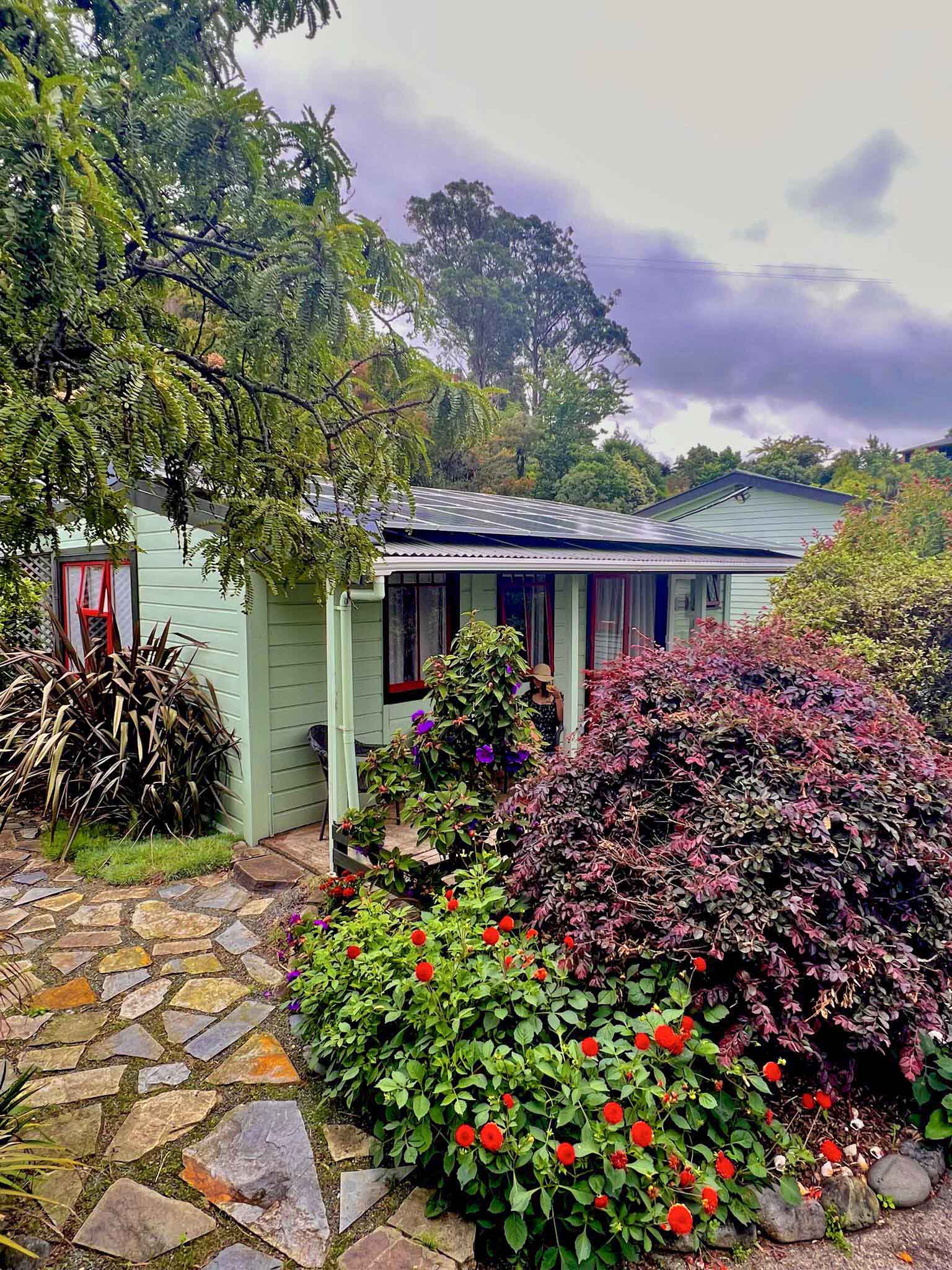 Exterior view of the Family Cottage at the Station House Motel in Collingwood, surrounded by gardens and colorful flowers.